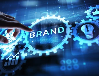 Eine Hand berührt leuchtend blaue Zahnräder; zentrales Zahnrad trägt BRAND, weitere Zahnräder mit Symbolen.