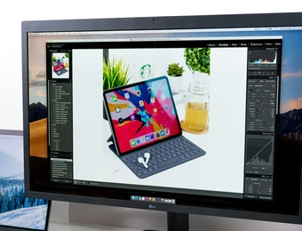 Monitor zeigt ein Foto eines iPad mit Tastaturhülle auf weißem Tisch; daneben Pflanzen.