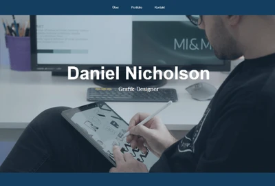 Person sitzt an einem Schreibtisch und zeichnet auf einem Grafik-Tablet mit Stylus; Monitor im Hintergrund.