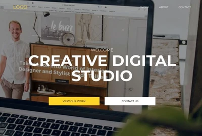 Laptop-Bildschirm zeigt CREATIVE DIGITAL STUDIO, Buttons VIEW OUR WORK und CONTACT US; Büro-Hintergrund mit Person links.