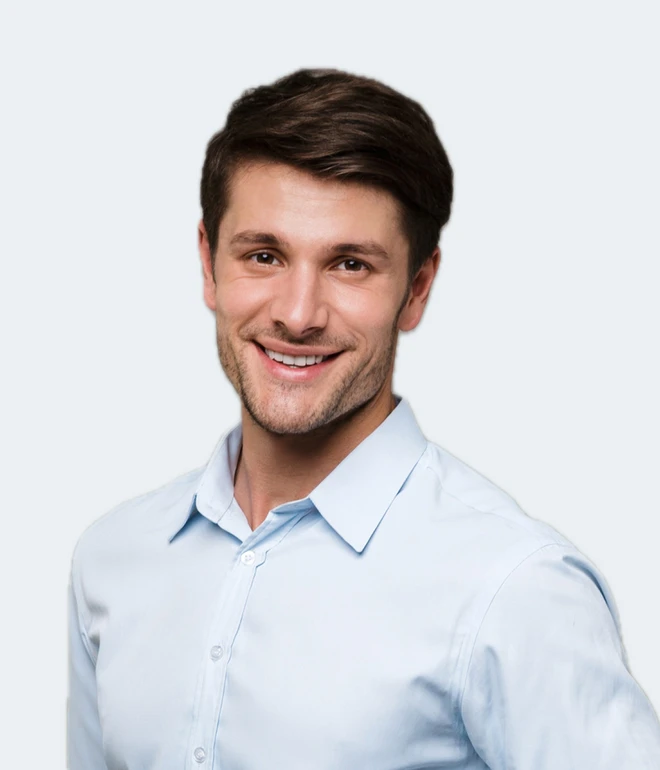 Junger Mann in hellblauem Hemd, lächelnd, vor hellem Hintergrund.