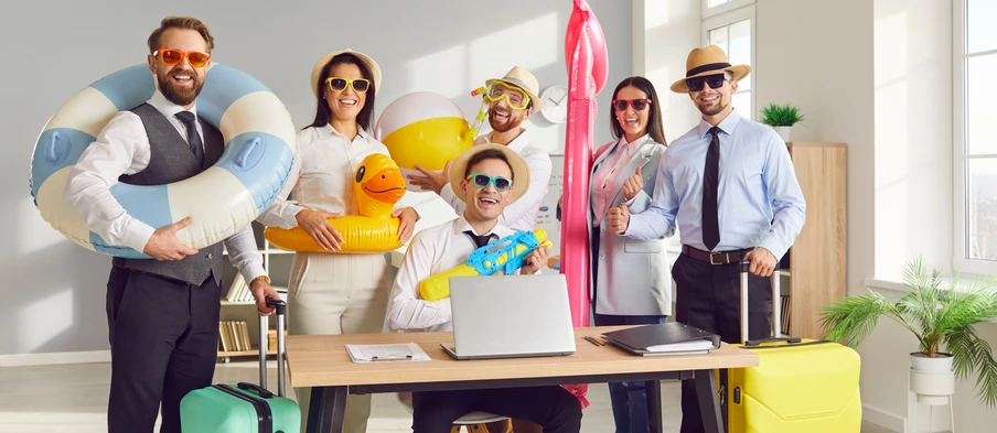 Gruppe von Personen in einem Büro; Sommer-Accessoires, aufblasbare Schwimmringe, Gelbe Gummiente, Laptop auf dem Tisch.