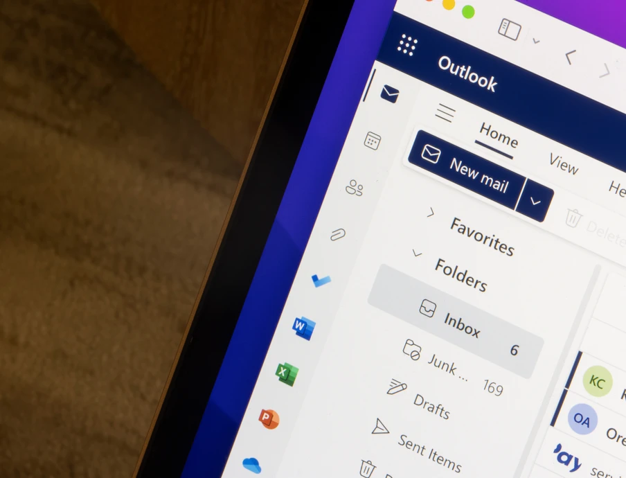 Bildschirm eines Laptops mit Outlook-Oberfläche; linke Seitenleiste zeigt Ordner (Inbox, Junk, Drafts) und Button 'New mail'.