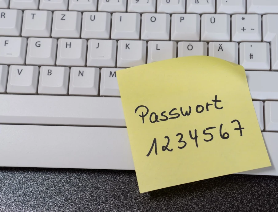 Gelber Klebezettel mit Passwort 1234567 liegt auf einer weißen Tastatur.