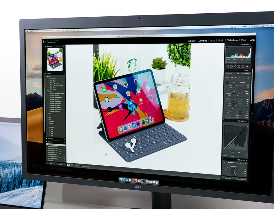 Monitor zeigt ein Foto eines iPad mit Tastaturhülle auf weißem Tisch; daneben Pflanzen.