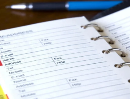 Offen geöffneter Aktenordner mit Ringbindung, farbigen Registerkarten und blauem Stift.