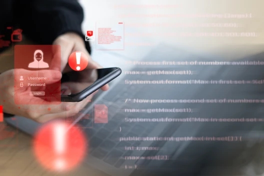 Nahaufnahme einer Hand, die ein Smartphone hält; rote Overlay-Symbole und Codezeilen im Hintergrund.