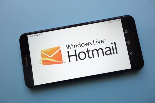 Schräg liegendes Smartphone auf blauem Hintergrund; Display zeigt Windows Live Hotmail-Logo.